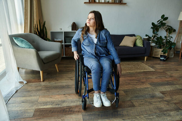 A young woman in a wheelchair sits in a modern apartment, gazing out the window, contemplating the day ahead.