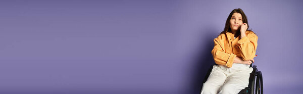 A young woman with long dark hair sits in a wheelchair and ponders thoughtfully in a studio with a purple backdrop.