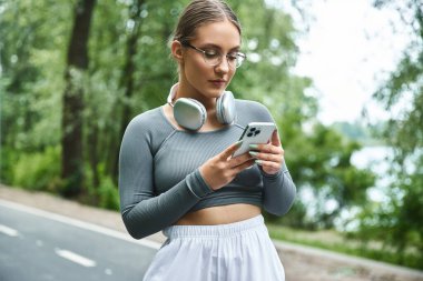Genç bir kadın spor yapmadan önce akıllı telefonuna bağlanır, spor yapma tutkusunu benimser..