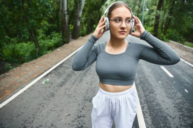 A determined young woman embraces outdoor fitness, wearing sportswear and a prosthetic leg. clipart