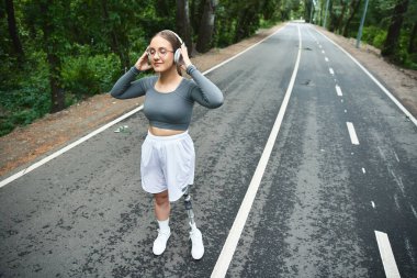 Protez bacaklı kararlı bir kadın açık havayı kucaklıyor, spor yapıyor ve temiz havanın tadını çıkarıyor..