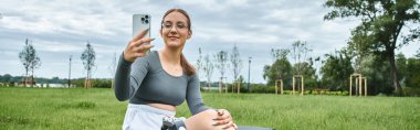 Protez bacaklı genç bir kadın spor yaparken selfie çekerken gülümsüyor..