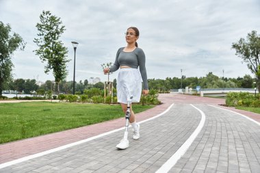 Protez bacaklı kararlı bir kadın spor kıyafetlerini giyerken açık hava fitnesini kucaklıyor..