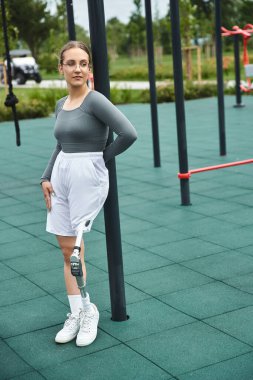 Kararlı genç bir kadın enerjik bir fitness parkında egzersiz yaparken tek bacağının üzerinde zarifçe dengede durur..