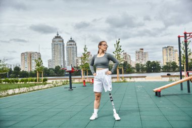 Kararlı genç bir kadın güvenli bir şekilde dışarıda egzersiz yapıyor, protez bacağıyla fitness ve doğayı kucaklıyor..