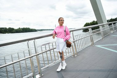 Protez bacaklı kararlı genç bir kadın açık havada su kenarında yürüyor..