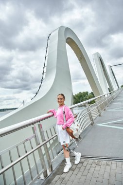 Protez bacaklı genç bir kadın dışarıda, güzel bir köprüde egzersiz yaparken spor yapmayı benimsiyor..