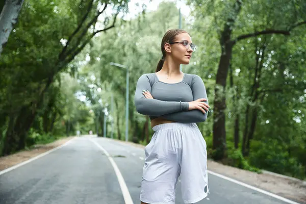 stock image A young woman confidently exercises outdoors, in the lush greenery.