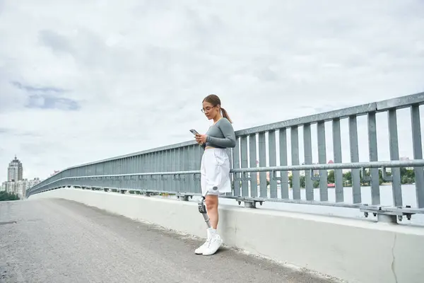 stock image A young woman in sportswear is actively enjoying her outdoor workout while using a smartphone.