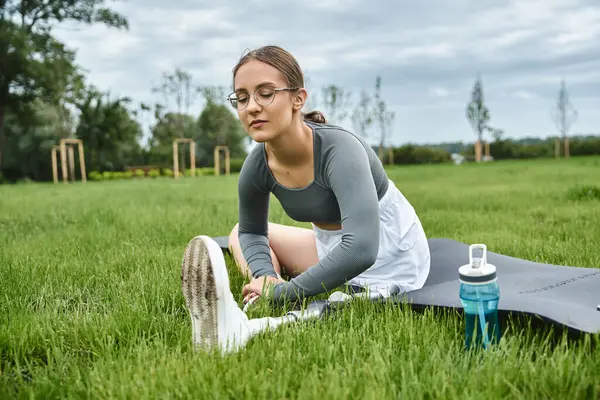 stock image A dedicated young woman stretches outdoors, showcasing her active lifestyle and resilience.