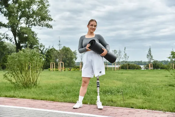 stock image A determined young woman in sportswear enjoys an outdoor workout with her yoga mat in hand.