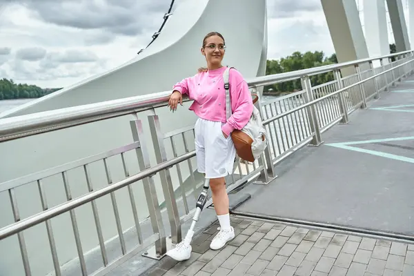 stock image A young woman with a prosthetic leg smiles, embracing an active lifestyle while outdoors.