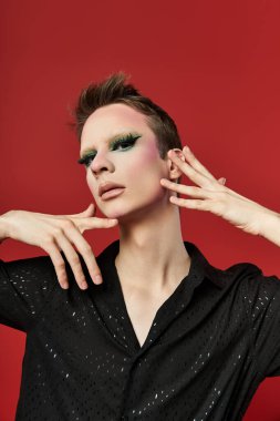 Genç bir travesti, dinamik pozlarla şık kıyafetler ve çarpıcı makyajlar sergiliyor..