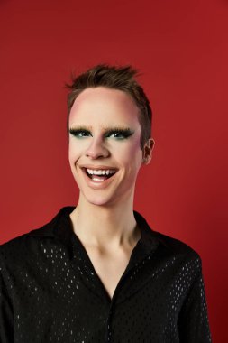 Genç bir drag sanatçısı çarpıcı moda kıyafetleriyle neşeli poz verir..