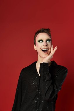 Genç bir travesti neşeli bir ifadeyle şık kıyafetler sergiliyor..