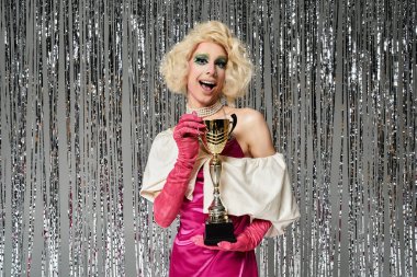 Canlı genç bir drag sanatçısı pırıl pırıl dekorasyonlar arasında neşeyle poz verir..