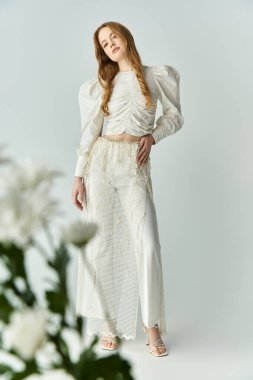 Güzel bir kadın çiçeklerin yanında zarifçe poz verir..