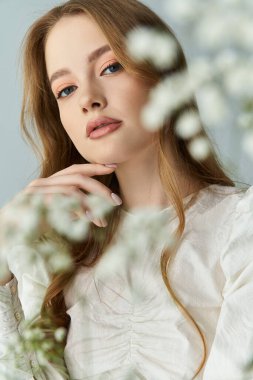 Çekici bir kadın nazikçe çiçeklerle poz verir, zarafet ve zarafetle..