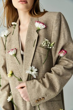 Zarif bir şekilde, taze çiçeklerle süslenmiş keten bir ceket sergileniyor..