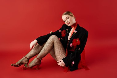 Çiçeklerle çevrili şık bir genç kadın pozuyla büyülüyor..