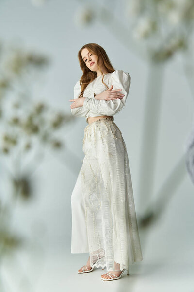 Изящная молодая женщина уверенно стоит среди нежных цветов.