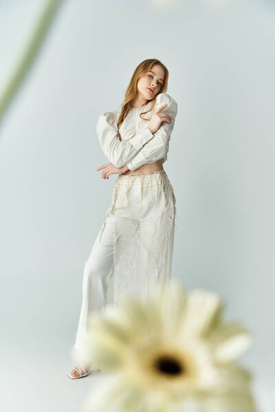 Молодая женщина безмятежно позирует в окружении мягких цветов и нежного света.