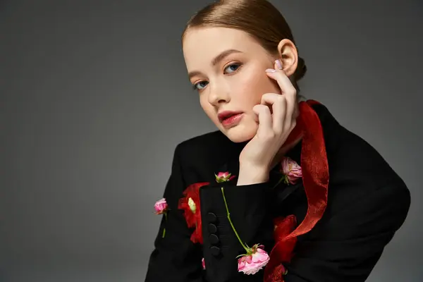 stock image A young woman gently touches her face amidst vibrant floral accents.