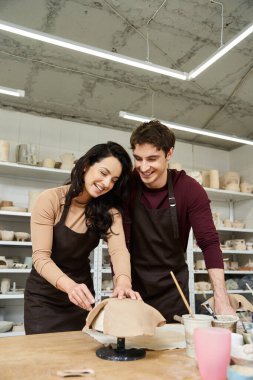 A loving couple shapes clay during a pottery session in a contemporary studio. clipart