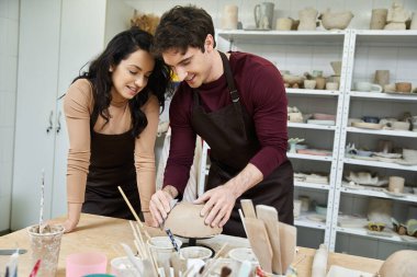 A couple lovingly crafts pottery in a contemporary workspace. clipart