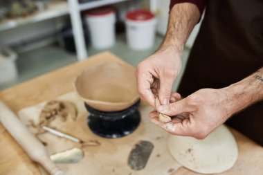 Hard working young man with apron making pottery. clipart