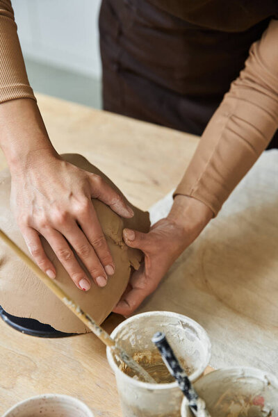 Ambitious woman making pottery in well lit studio.