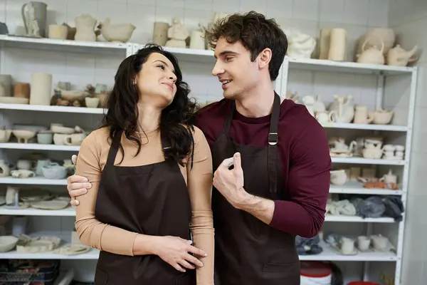 stock image A couple joyfully shapes clay while sharing smiles in their studio.