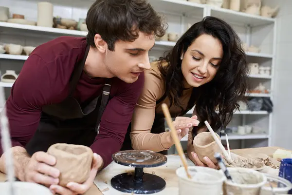 stock image A couple shares a creative moment as they shape clay pots together.