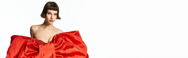 Стильная молодая женщина демонстрирует свое яркое красное платье с драматическим бантом.