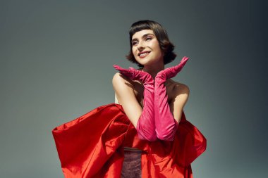 A stylish young woman flaunts her chic red dress with a dramatic bow and pink gloves. clipart