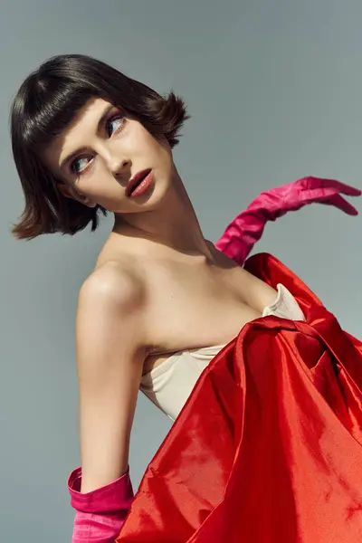 stock image A stylish young woman with a bob haircut showcases her vibrant red ensemble.