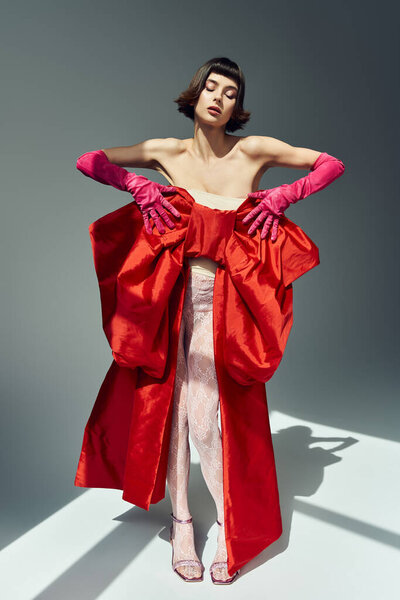Красивая женщина демонстрирует свой стиль моды вперед в ярком красном одеянии.