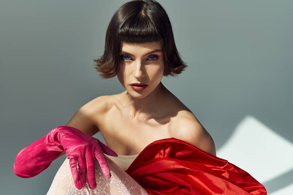 Захватывающая молодая женщина в потрясающем красном платье источает уверенность и стиль.