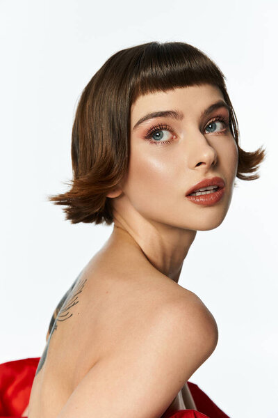 A captivating young woman poses confidently with a stylish red dress and elegant hairstyle.