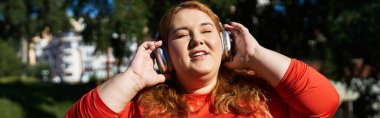 Neşeli, iri yarı bir kadın müzik dinlerken dışarıda egzersiz yapıyor..