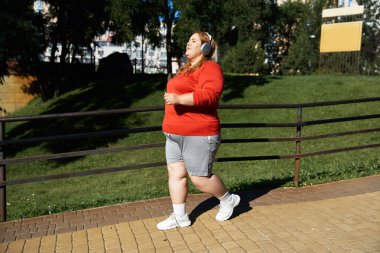 Neşeli bir kadın dışarıda egzersiz yapıyor, spor yolculuğunun tadını çıkarıyor..