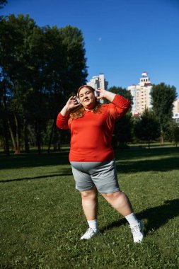 Güzel bir kadın yemyeşil ve güneşli gökyüzünün ortasında spor yapıyor..