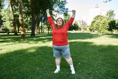 Güneşli bir parkta spor yapan bir kadın spor yapıyor. Zindelik ve kendine güveni kucaklıyor..