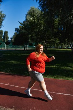 Güzel, iri yarı bir kadın parkta koşmaktan zevk alır, spor yolculuğunu benimser..