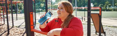 A joyful woman replenishes with water after a workout in the park. clipart