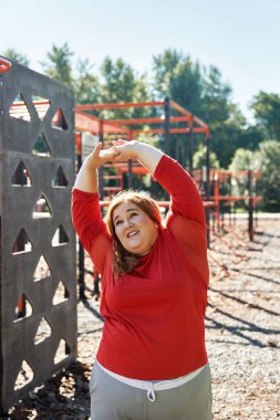Kendine güvenen bir kadın, açık mavi gökyüzünün altında egzersiz rutininden zevk alır..