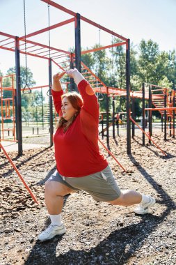 A dedicated woman practices lunging exercises in a lively park. clipart