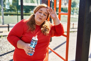 Bir kadın dışarıda egzersiz yaptıktan sonra dinlenir. Parktaki spor yolculuğunun tadını çıkarır..