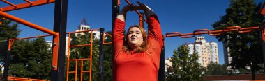 A plus size woman enjoys outdoor exercise while stretching in a vibrant park. clipart