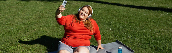 A woman exercises happily in the park while listening to music.